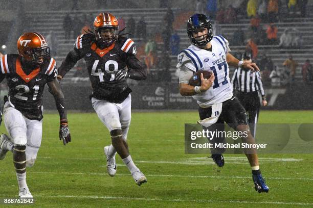 Quarterback Daniel Jones of the Duke Blue Devils rushes while being pursued by linebacker Tremaine Edmunds and safety Reggie Floyd of the Virginia...