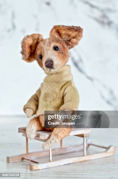 toy teddy dog sitiing on a sledge on white background - blue sweater stockfoto's en -beelden