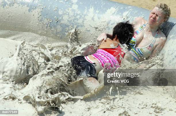 Participants compete during the final of the international women's mud wrestling contest along the East Lake on May 10, 2009 in Wuhan of Hubei...