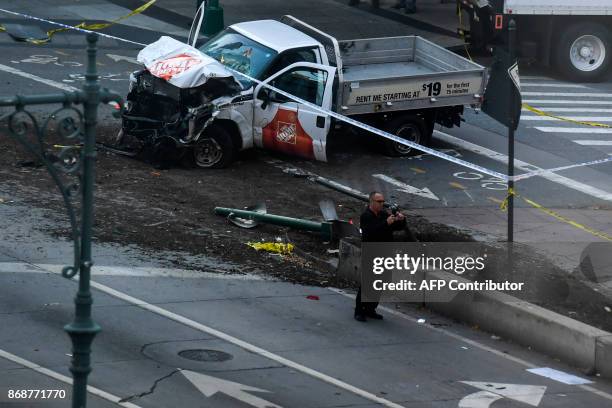 An investigator takes pictures with his phone near a pickup truck following an incident in New York on October 31, 2017. A pickup driver killed eight...