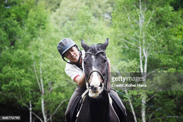 man riding on the horse and stroking it in the ranch in the rain - horseback riding ストックフォトと画像