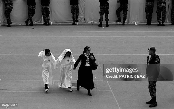 Christian nun hold hands with two Jordanian Christian girls as she walks past a Jordanian soldier standing guard at Amman's stadium where Pope...