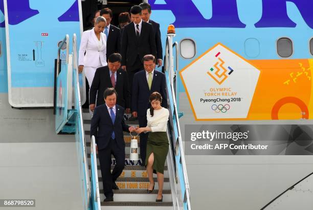 South Korea's Culture, Sports and Tourism Minister Do Jong-Whan and former figure skating champion Yuna Kim carry the Olympic flame upon its arrival...