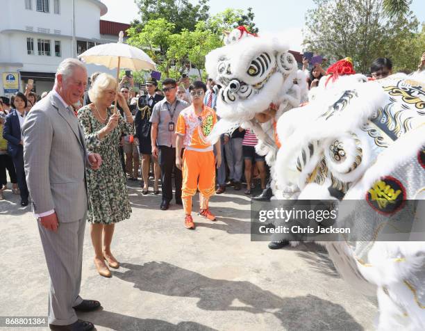 Prince Charles, Prince of Wales and Camilla, Duchess of Cornwall are greeted by lion dancers upon arrival at Tiong Bahru Market on November 1, 2017...