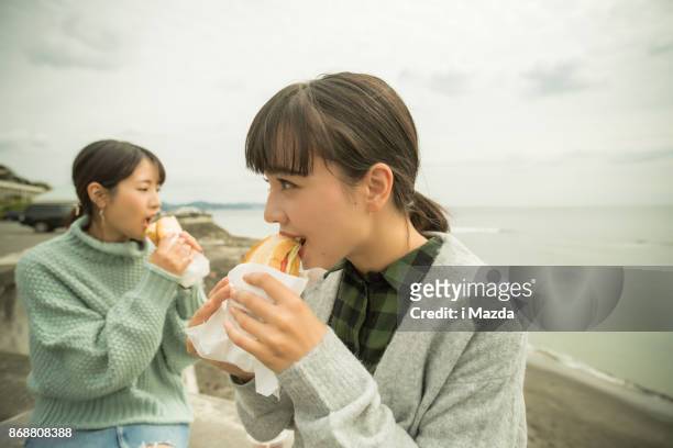 prendono un pranzo sandwich nel parcheggio sulla spiaggia. . - girls laughing eating sandwich foto e immagini stock