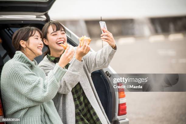 almorzar un sandwich en el estacionamiento frente a la playa. . - japanese girl fotografías e imágenes de stock