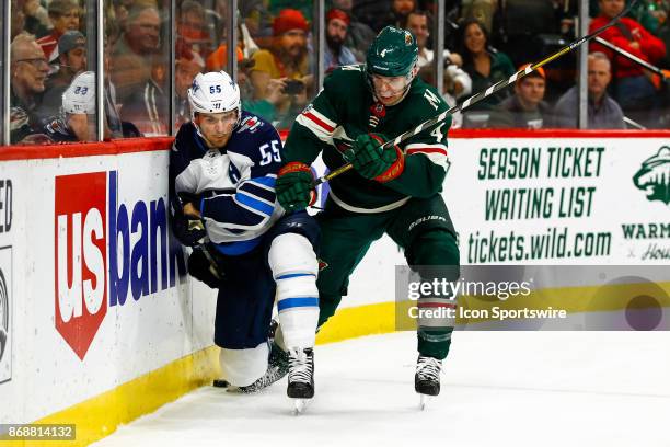 Minnesota Wild defenseman Mike Reilly checks Winnipeg Jets center Mark Scheifele along the boards during the Central Division game between the...