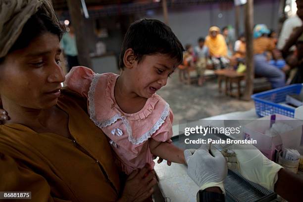 Rohingya girl is held by her mother asshe gets her finger pricked for the malaria test at special clinic for malaria on May 4, 2009 in Sittwe, Arakan...