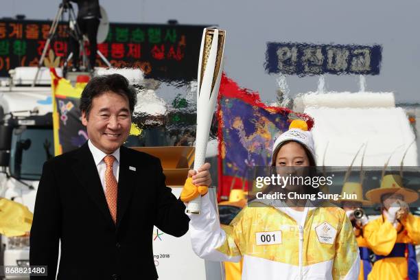 South Korean prime minister Lee Nak-yon and First torch bearer, South Korean figure skater You Young hold the PyeongChang 2018 Winter Olympics torch...