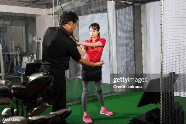 a woman practicing at a golf studio and a man with a coach. - golf simulator stock pictures, royalty-free photos & images