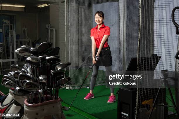 a woman with a smile at a golf studio. - putting indoors stock pictures, royalty-free photos & images