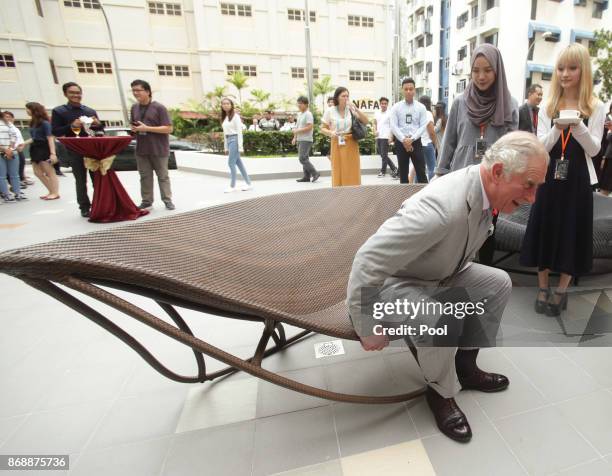 Prince Charles, Prince of Wales sits on an outdoor rocking daybed, designed by students during his visit to the Nanyang Academy of Fine Arts on...