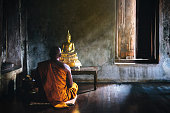 A monk is worshiping and meditating in front of the golden Buddha as part of Buddhist activities.Focus on the Buddha