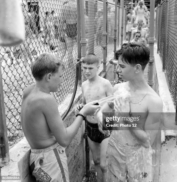 Glen Echo, Maryland, USA. An attendant washing the sand from people who are going to the swimming pool for the beach at the Glen Echo amusement park....