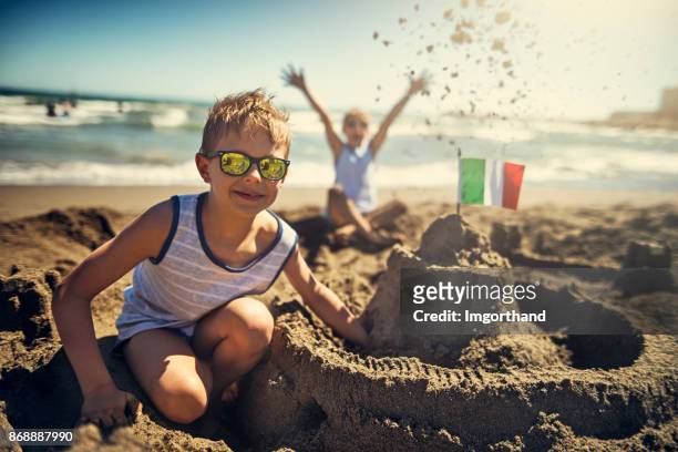 zwei jungen bauen eine sandburg am strand von italienischen - kind sandburg stock-fotos und bilder