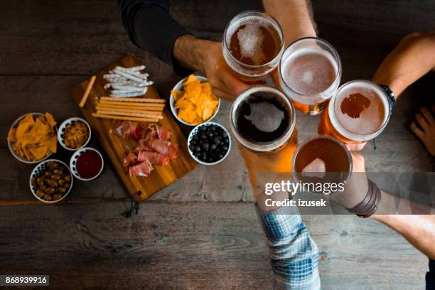 top view of friends toasting with beer glasses in the pub - beer glass from above stock pictures, royalty-free photos & images