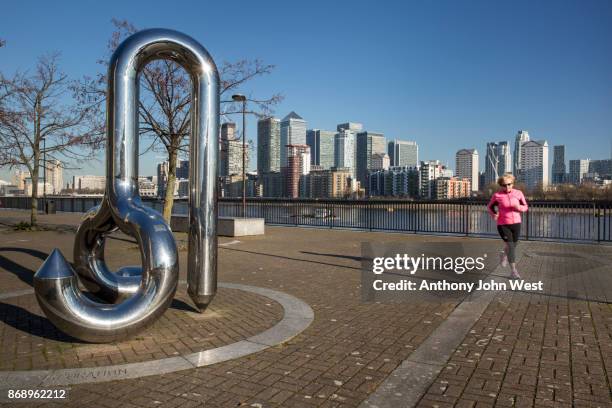 curlicue, a sculpture by william pye, greenland dock, with the international banks on canary wharf across the river, london - modern sculpture stock pictures, royalty-free photos & images