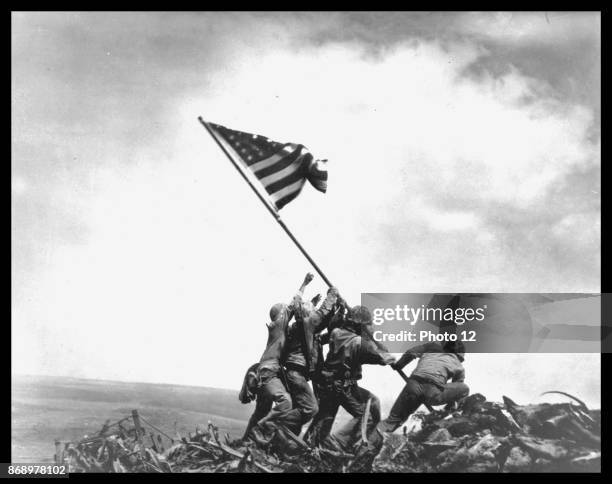 View of members of the United States Marine Corps 5th Division as they raise an American flag on Mount Suribachi during the Battle of Iwo Jima,...