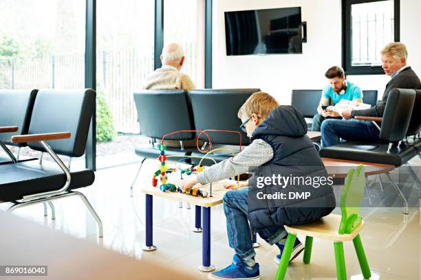 ragazzino che gioca in sala d'attesa in clinica - dentista bambini foto e immagini stock