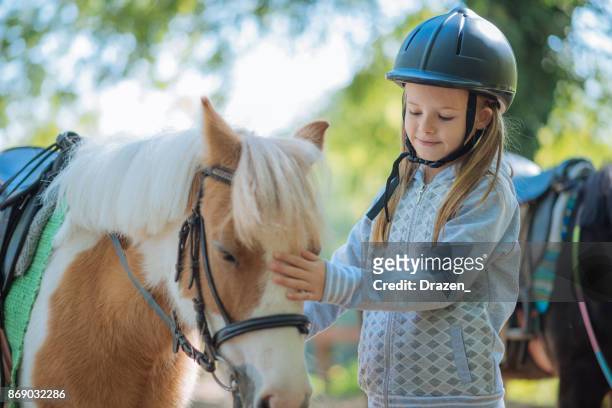 彼女のポニー馬を抱きしめる少女 - 乗馬帽 ストックフォトと画像