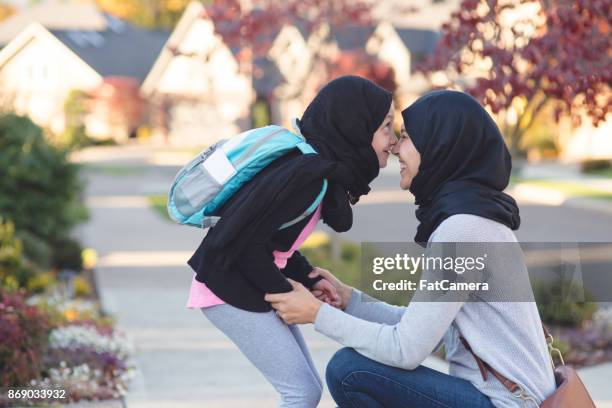 moslim moeder en dochter begroeten speels elkaar na school - funny fat women stockfoto's en -beelden