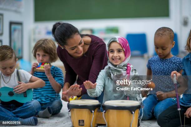 moslim meisje geniet van muziek klas op school met haar vrienden. - culturen stockfoto's en -beelden