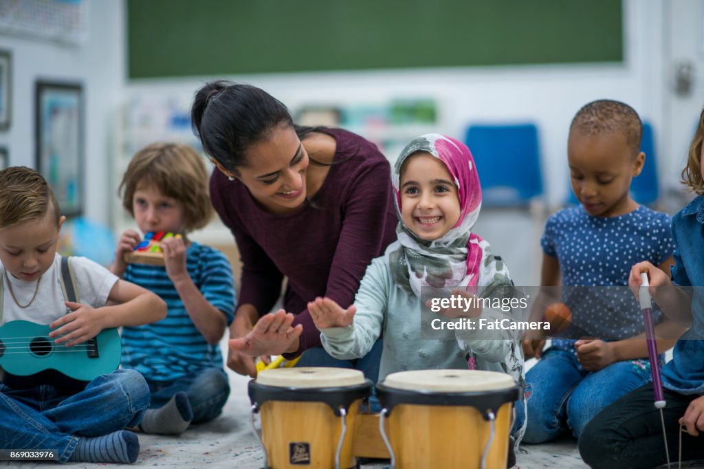 Little Muslim girl enjoy music class at school with her friends.