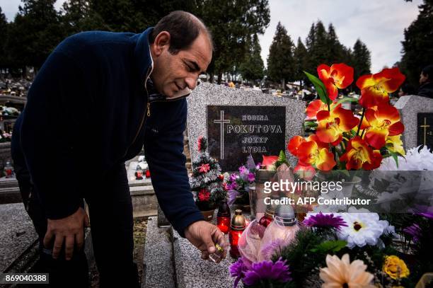 Roman Pokuta pours a liqueur spirit on a grave of his deceased relative as a traditional custom of Roma people in Eastern Slovakia, in Levoca on...