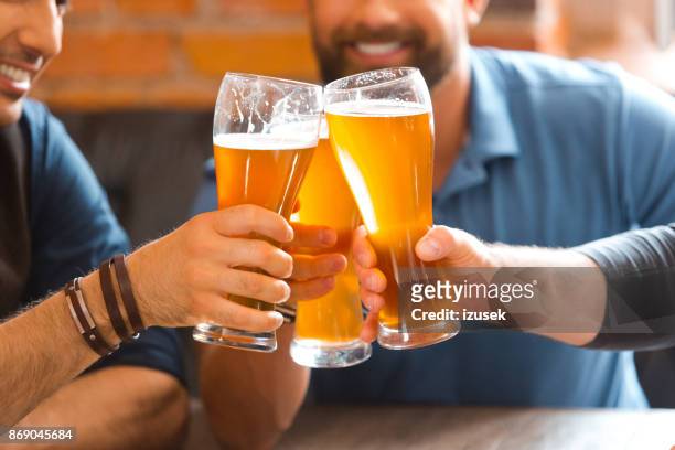 three men toasting with beer glasses in the pub - beer cheers stock pictures, royalty-free photos & images