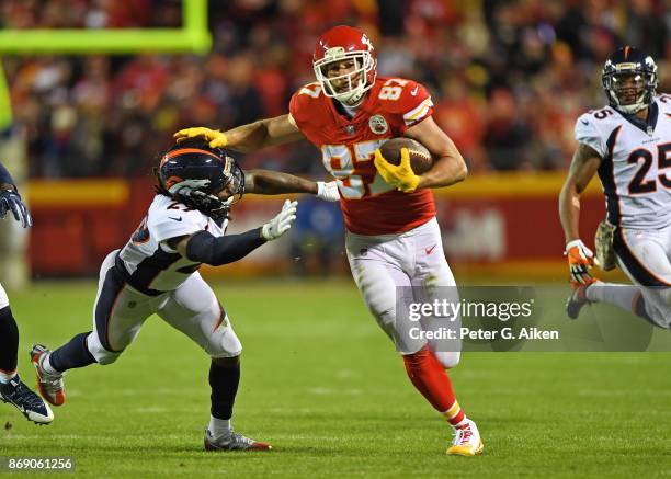 Tight end Travis Kelce of the Kansas City Chiefs runs up field after catching a pass against pressure from defender Bradley Roby of the Denver...