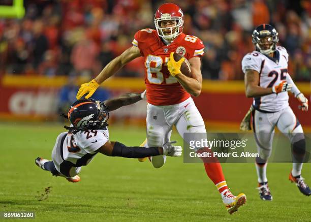 Tight end Travis Kelce of the Kansas City Chiefs runs up field after catching a pass against pressure from defender Bradley Roby of the Denver...