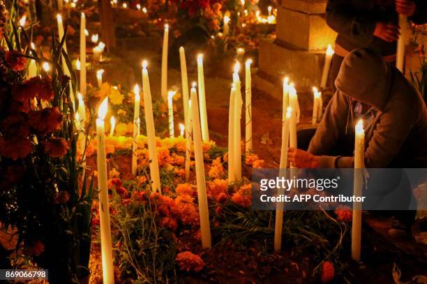 Relatives light candles in the tomb of their loved one during the "Alumbrada" a celebration in the framework of All Saints Day, in Santa Maria...