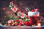 Advent calendar and Santa's shoe with gifts on rustic wooden background