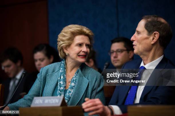 Sen. Debbie Stabenow talks to Sen. Ron Wyden during a meeting about the GOP tax plan held by the Democratic Policy and Communications Committee on...