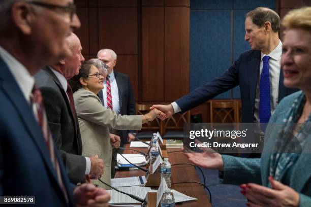 Sen. Ron Wyden shakes hands with Luz Arevalo, attorney at a low-income tax preparation clinic in Boston, at the start of a meeting about the GOP tax...