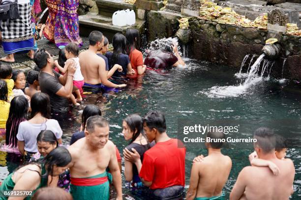 scene of water purification ritual at tirta empul temple - tirta empul temple stock pictures, royalty-free photos & images