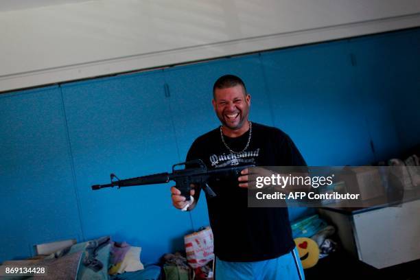 Daniel Rivera smiles as he shows a toy gun in a classroom turned bedroom in Barranquitas, Puerto Rico October 31, 2017. Twenty people from...