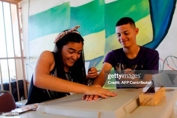 Sharielys Morales and Jeremy Luis Vazquez play cards at the school lobby in Barranquitas, Puerto Rico October 31, 2017. Twenty people from...