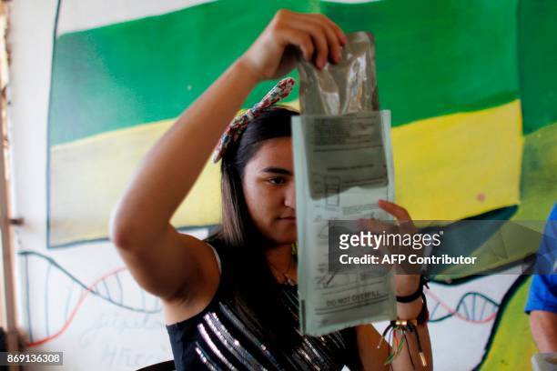 Sharielys Morales puts a military Meal Ready to Eat food package into a heat pack in Barranquitas, Puerto Rico October 31, 2017. Twenty people from...