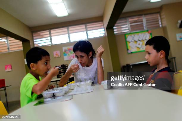 Elsa Diaz takes breakfast at the school canteen with her two children, Angel Elier Rivera and Adriel Isaac Rosario in Barranquitas, Puerto Rico...
