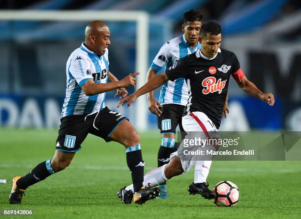 Sergio Aquino of Libertad fights for the ball with Arevalo Rios of Racing Club during a second leg match between Racing Club and Libertad as part of...