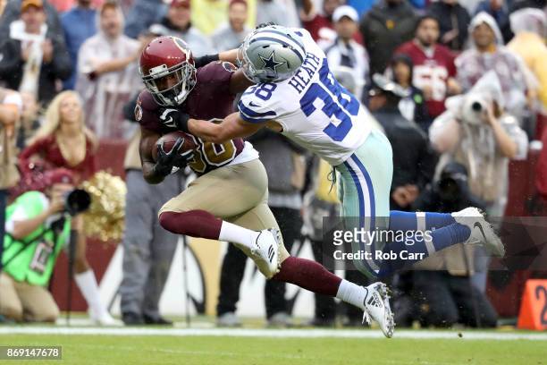 Wide receiver Jamison Crowder of the Washington Redskins is tackled by strong safety Jeff Heath of the Dallas Cowboys after catching a pass at FedEx...