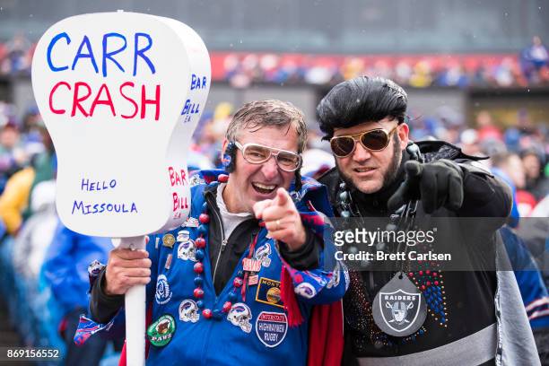 Fans dressed as Elvis Presley cheer for their respective teams during the first half of the game between the Buffalo Bills and the Oakland Raiders at...