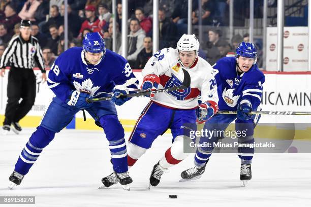 Daniel Audette of the Laval Rocket tries to skate the puck in-between Colin Greening and Adam Brooks of the Toronto Marlies during the AHL game at...