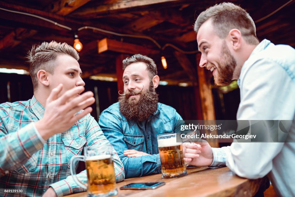 Handsome Man Telling Funny Story to his Best Friends While Drinking Beer in a Pub