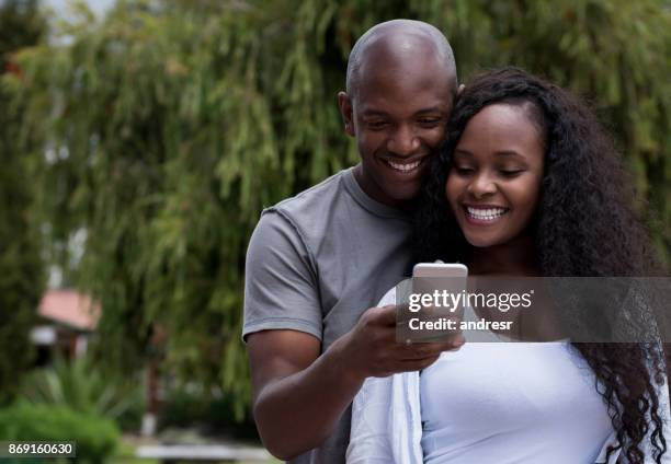 african american couple looking at social media on a cell phone - man atm smile stock pictures, royalty-free photos & images