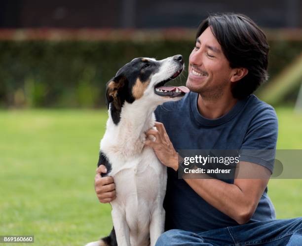 hombre feliz jugando con su perro al aire libre - adopción fotografías e imágenes de stock