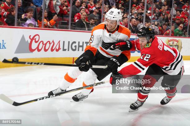 Mark Alt of the Philadelphia Flyers and Alex DeBrincat of the Chicago Blackhawks chase the puck in the second period at the United Center on November...