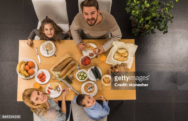 above view of young happy family eating at dining table. - high angle view family stock pictures, royalty-free photos & images