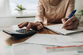 Close up of woman planning home budget and using calculator.